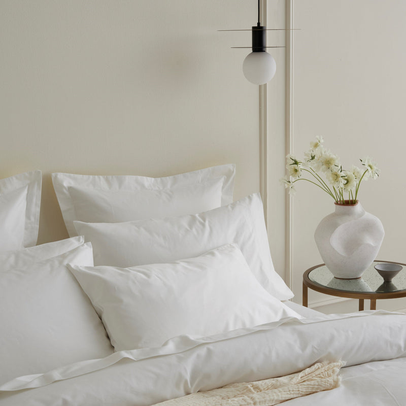 Bed styled with quilt cover and multiple pillows in a minimalist bedroom
